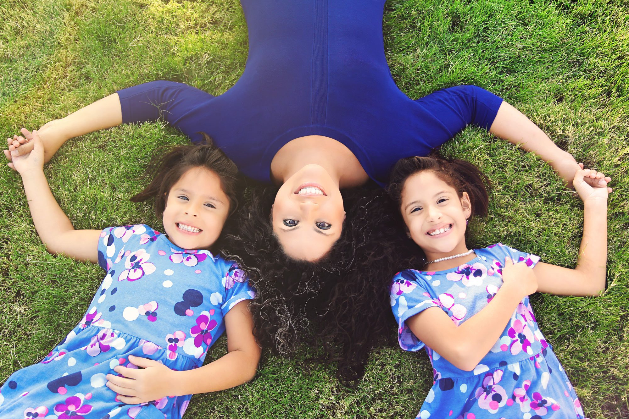 creative pose of mom lying in the grace with her 2 daughters