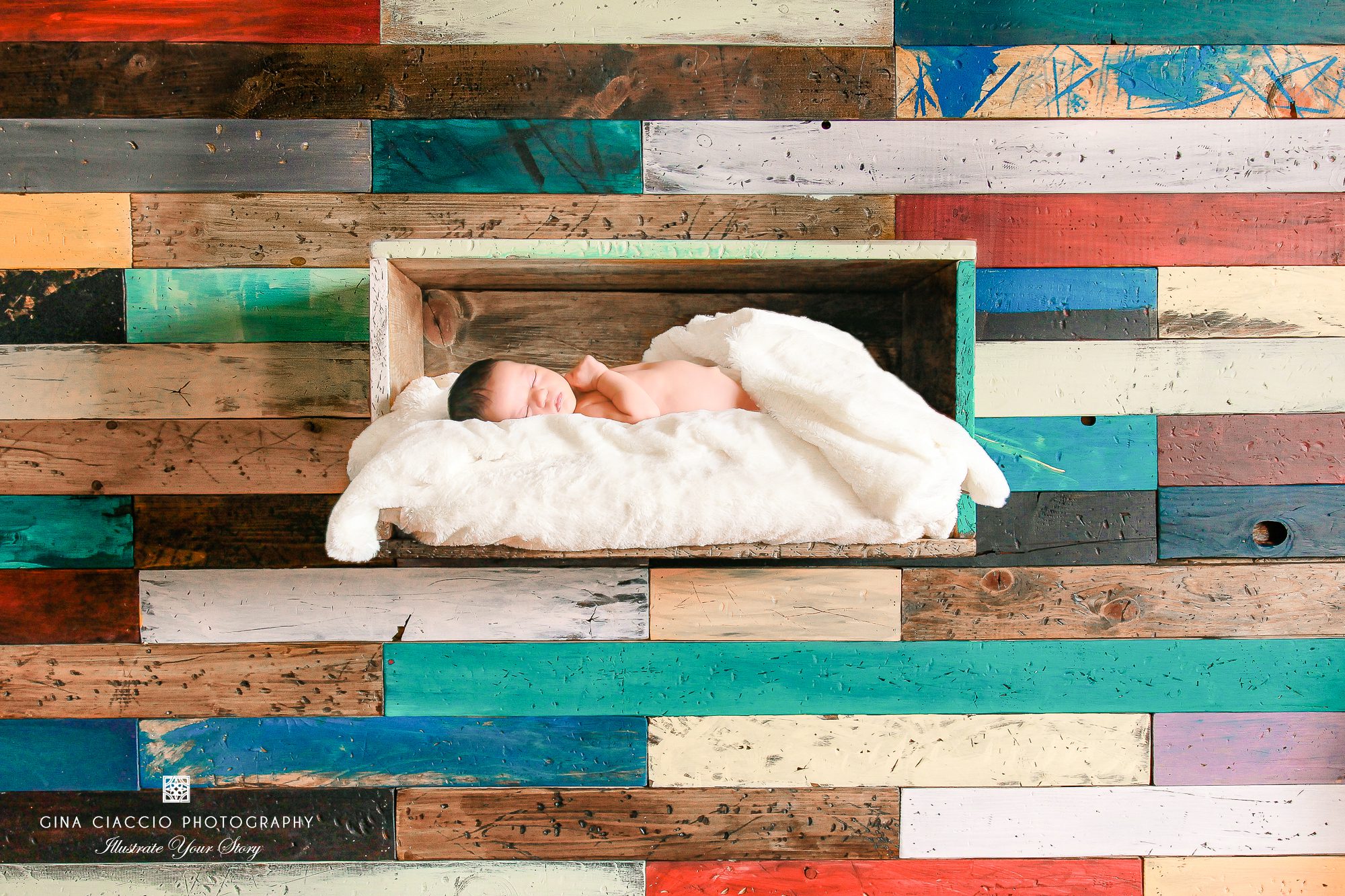 composite image of newborn baby boy on colorful reclaimed wood photo prop
