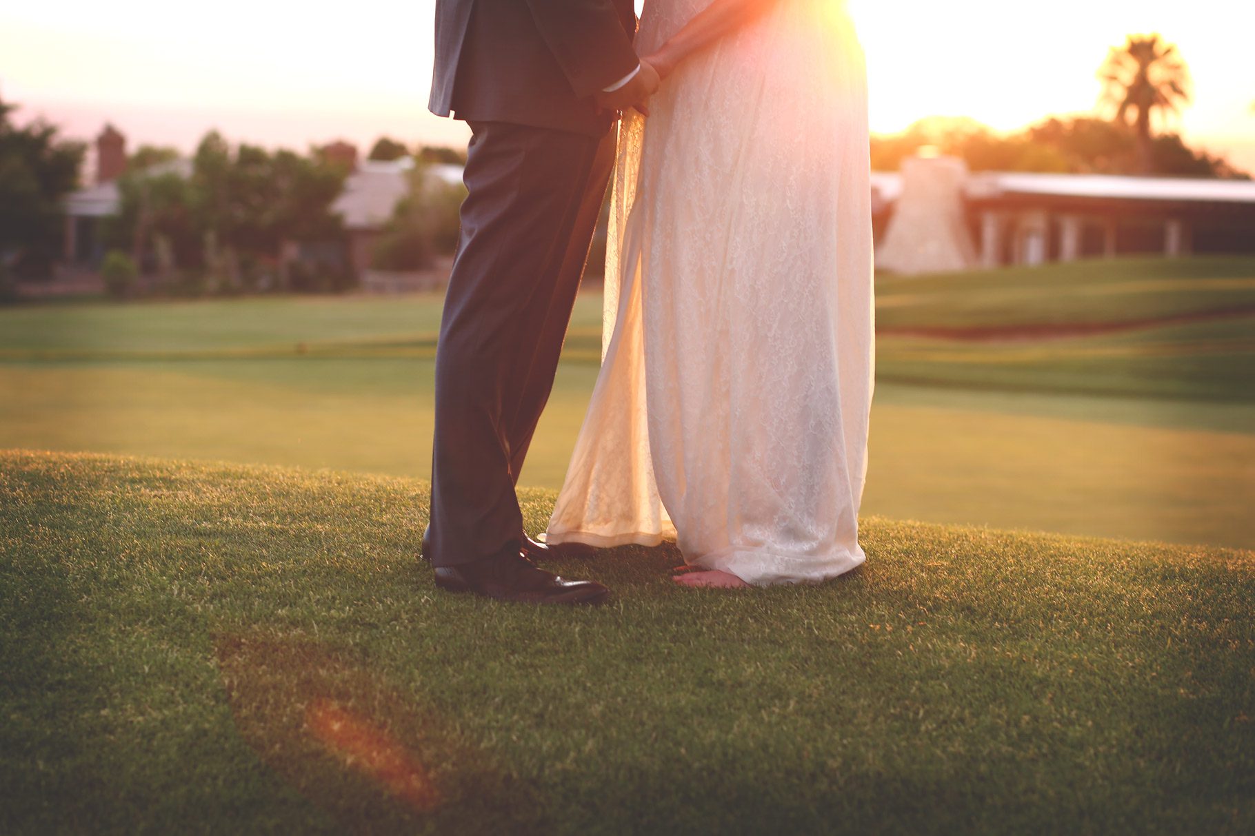 bride and groom hold hands at sunset on the golf course